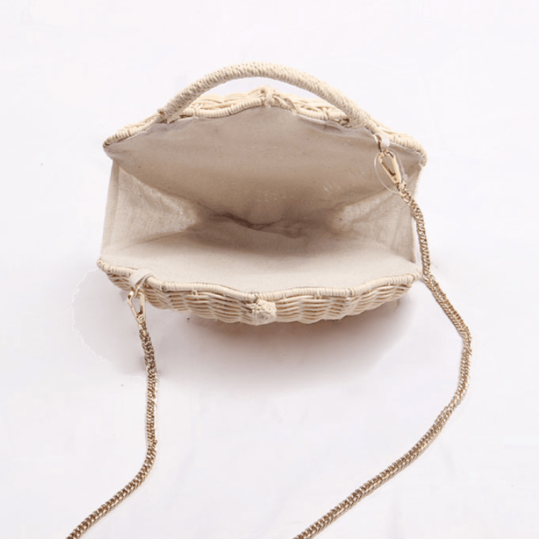 Interior view of a woven straw beach bag, featuring a chain strap and a spacious, stylish design.