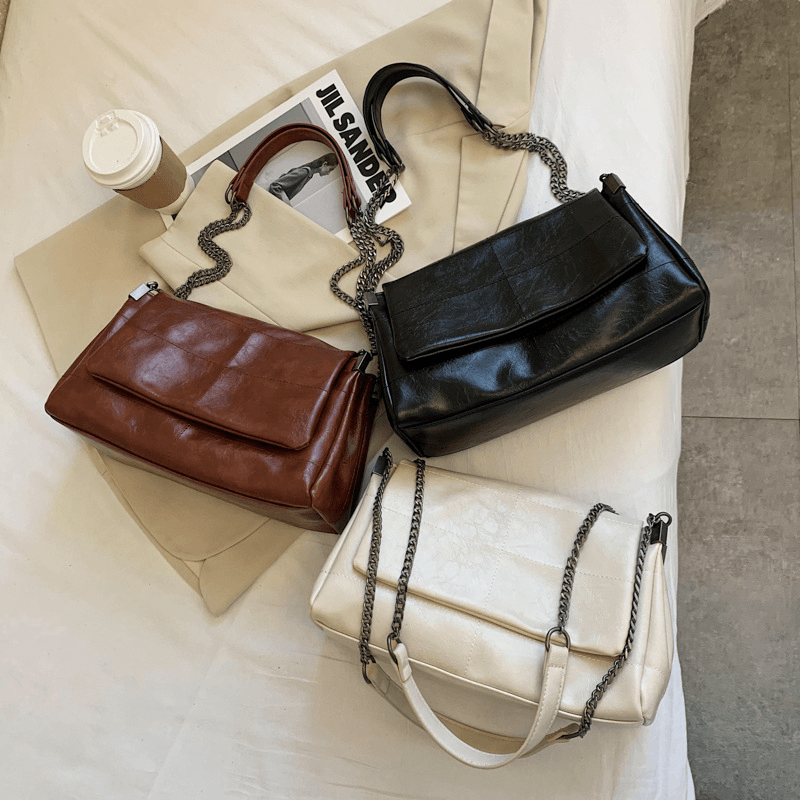 trendy PU leather small square bag collection in black, coffee, and beige on a bed with coffee cup.