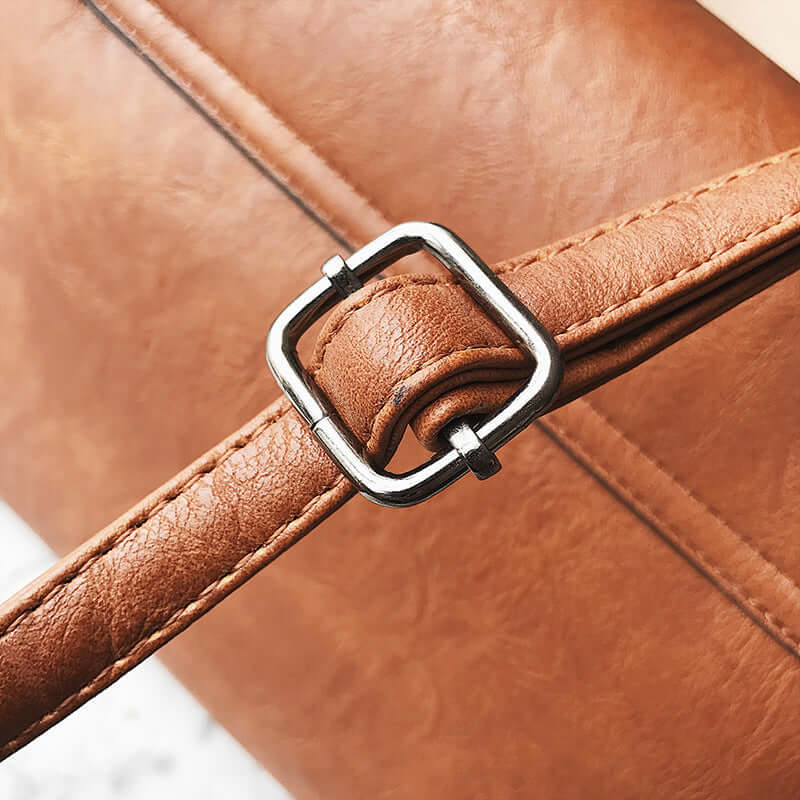 Close-up of the buckle detail on a stylish Messenger Bag, Commuter Bag, Small Square Bag in brown leather.