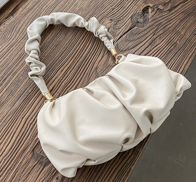 Cloud Bag, Shoulder Bag, Crossbody Bag on wooden table, stylish and versatile design with unique handle.