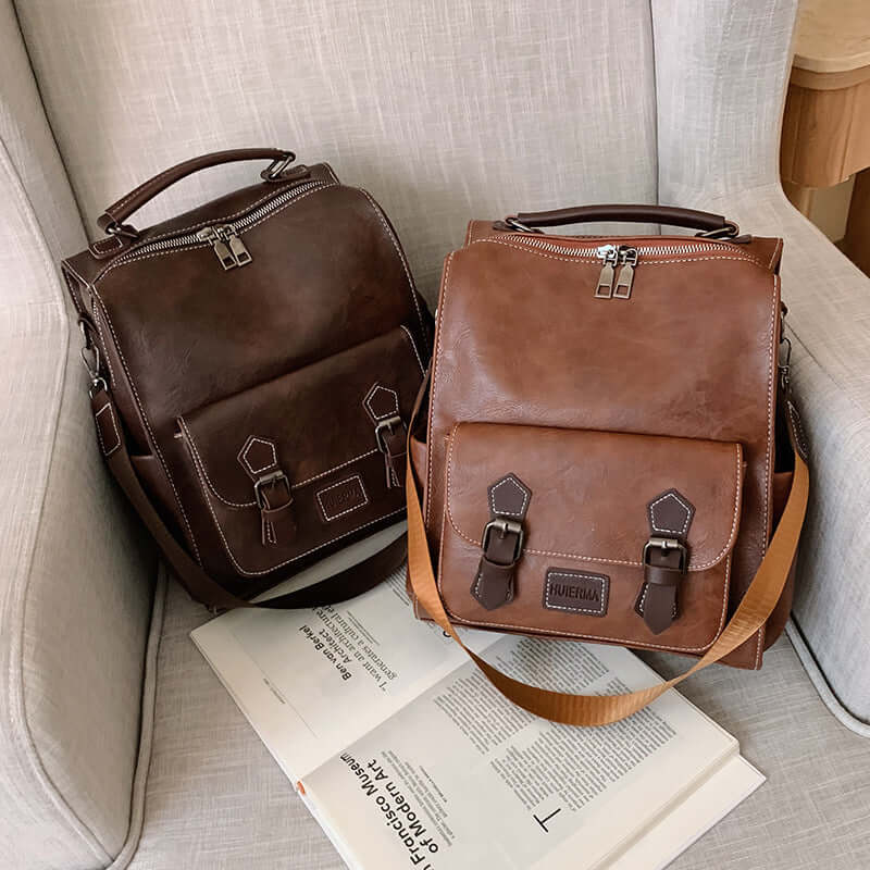Trendy vintage leather women's travel backpack in brown colors displayed on a sofa with magazines.