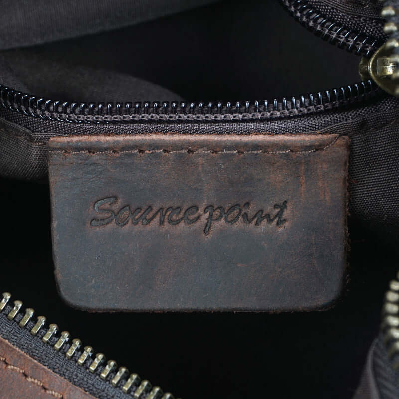 Leather crossbody messenger bag interior label showing Sourcepoint branding with zipper detail.