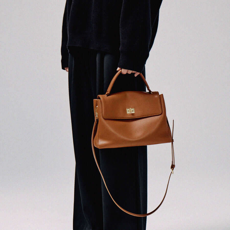 Large capacity cowhide crossbody bag in Caramel Brown being held by a person in a stylish outfit.