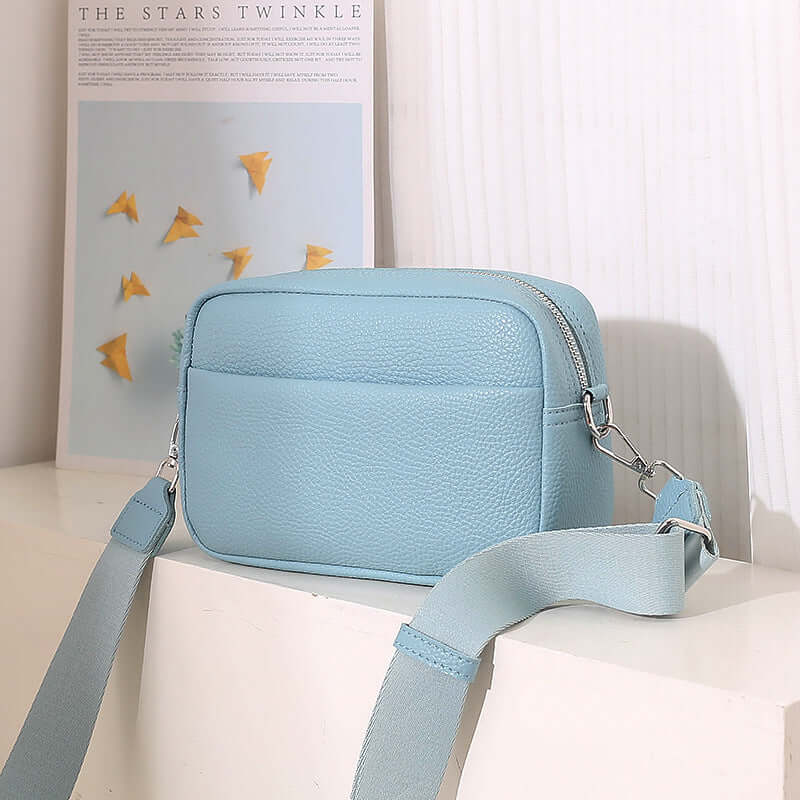 Solid Color Women's Messenger Bag with Wide Strap in light blue color on a table.