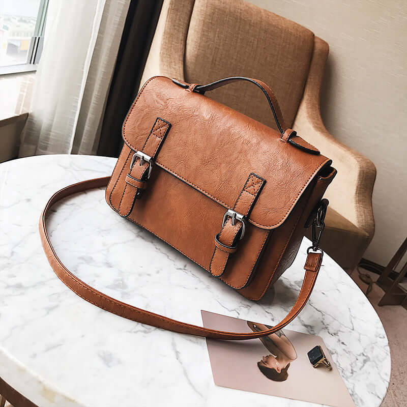 Stylish commuter messenger bag in brown PU leather on marble table, perfect for modern women on the go.