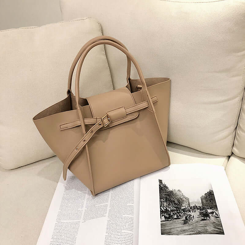 Chic crossbody shoulder bag in tan placed on a magazine, showcasing its stylish design and versatility.