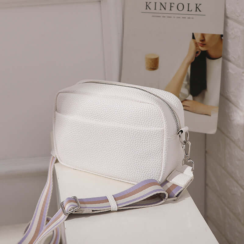 Solid Color Women's Messenger Bag with Wide Strap on a table, featuring a stylish design and wide strap for comfort.