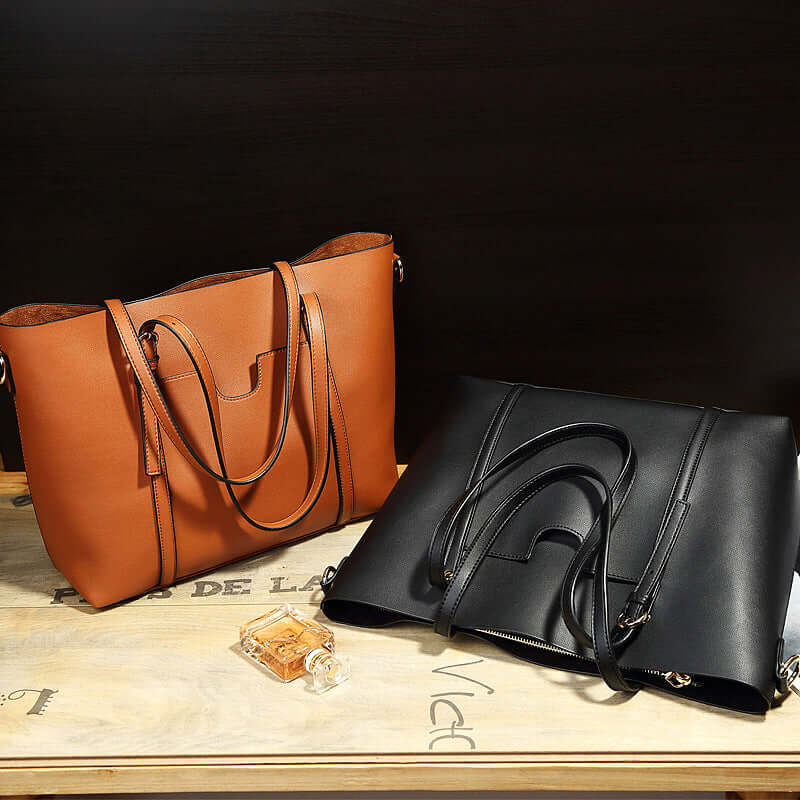 Two stylish bucket shoulder bags in brown and black leather on a wooden surface with a perfume bottle beside them.