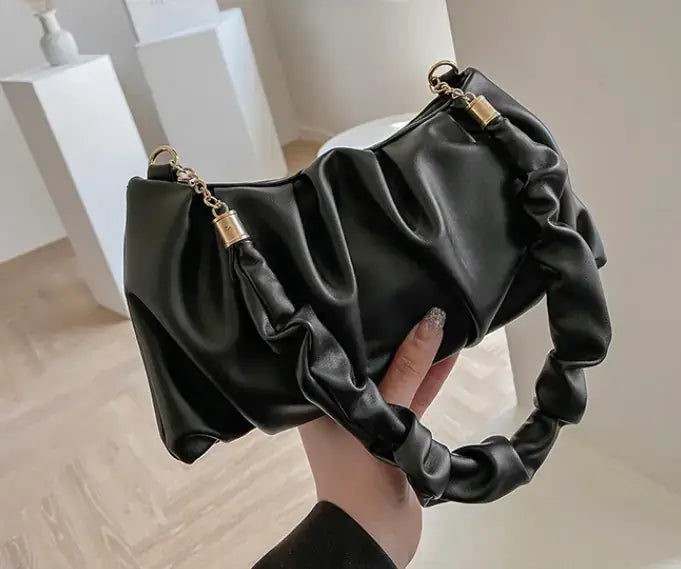 Cloud Bag, Shoulder Bag, Crossbody Bag held in a hand, featuring a stylish, ruffled design in black.