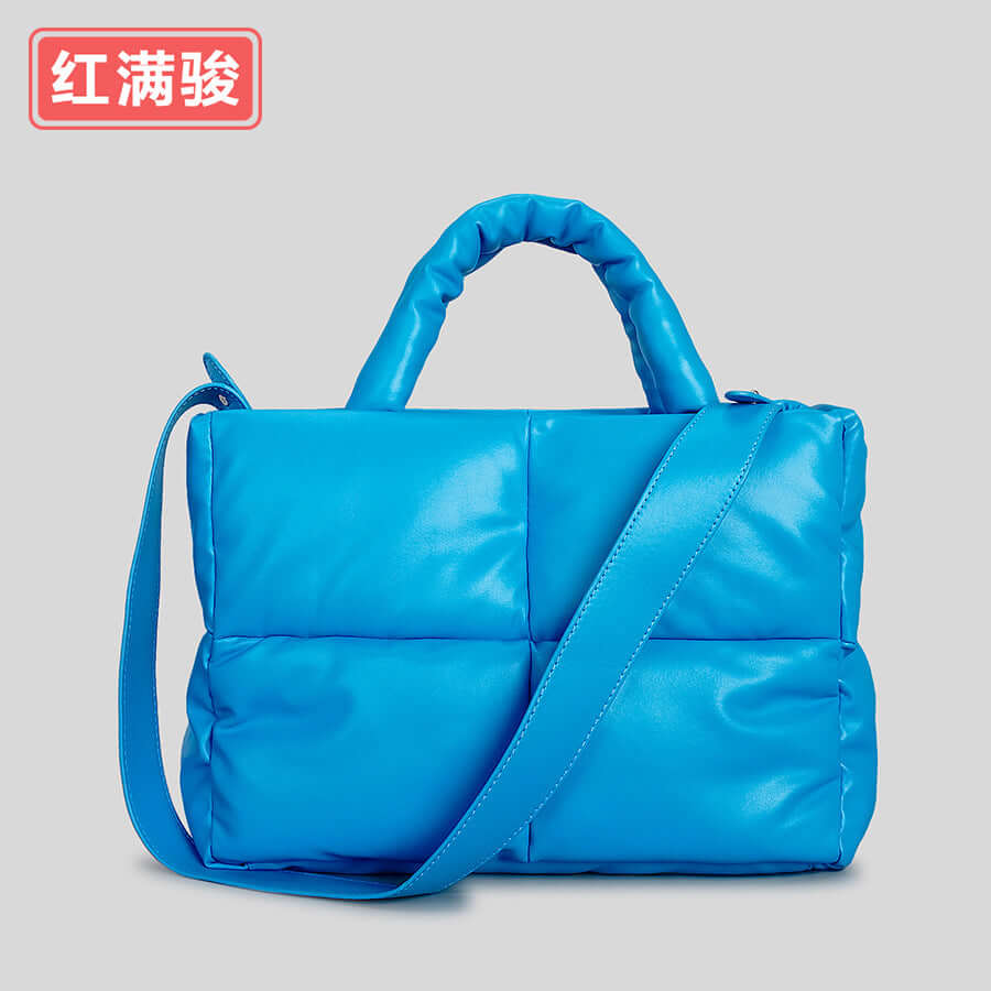 Women's quilted tote bag in vibrant blue with padded design and shoulder strap.