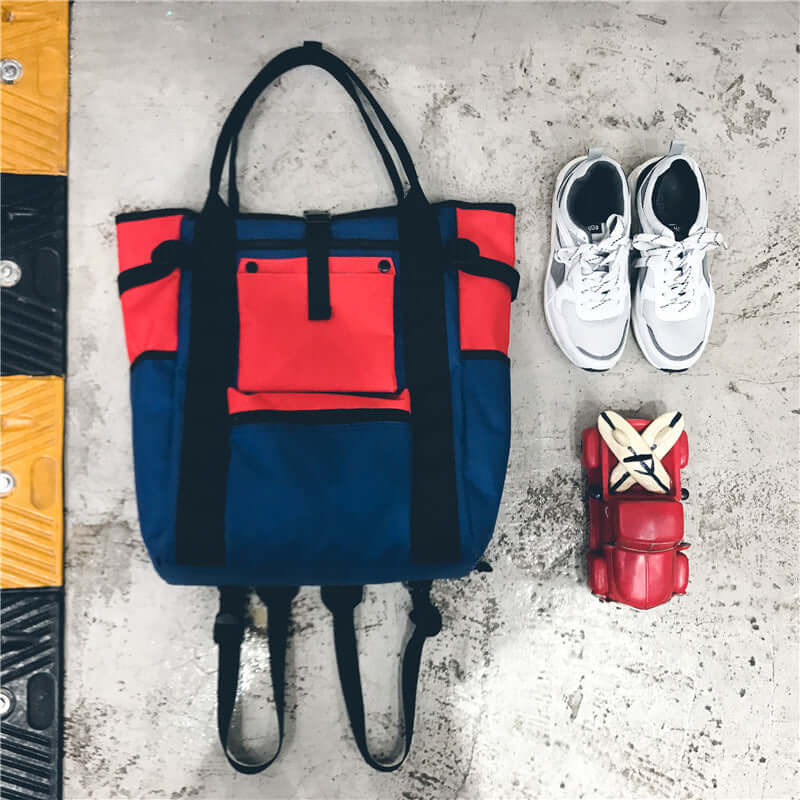 Trendy Canvas Backpack in blue and red color contrast with shoes and accessories on a concrete floor.