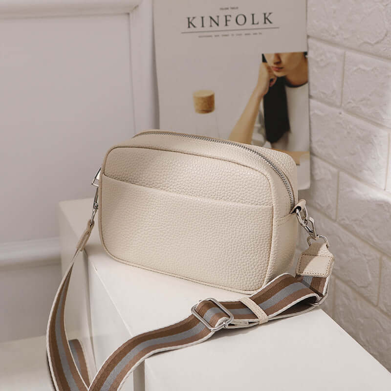 Solid Color Women's Messenger Bag with Wide Strap showcased on a table, highlighting its stylish design and functionality.