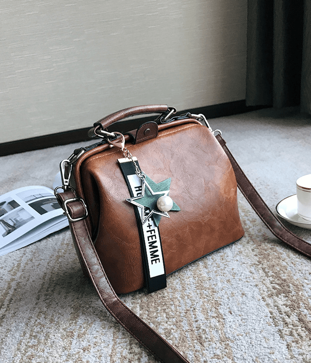 Chic doctor shoulder bag in brown PU leather with a star charm and detachable strap on a stylish surface.